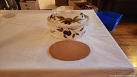 Top side view of oval ceramic baker with lid, showing fruit pattern and acorn knob on lid.