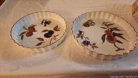 Two Royal Worcester Evesham quiche dishes with fruit designs placed side by side showing fronts.