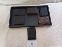 Six assorted leather wallets displayed in a black tray on a white surface.