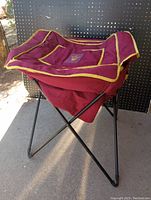 Photo shows maroon and yellow portable cooler with ASU logo on top, standing on black collapsible metal frame.