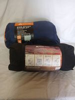 Sleeping bag and tent rolled up with labels visible showing product details