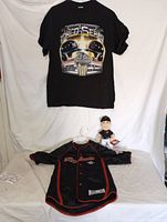 Photo showing all three items together: a black World Series T-shirt, a kids black button-up Diamondbacks shirt, and a small plush doll.