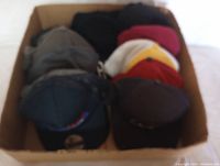 Top view of 12 assorted baseball hats in box showing various colors and styles