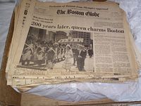 The Boston Globe newspaper showing headline about Queen charming Boston and photo of a ceremonial event.