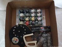Photo showing variety pack of NFL mini helmets in packaging and Pittsburgh Steelers mini helmet clock.