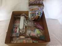 Overview of the lot with Be Dazzler box, applicator tool, glitter containers, and other accessories inside cardboard box