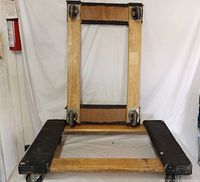 Wooden furniture dolly with metal swivel caster wheels seen from an angled top-front view.