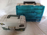 Two Plano tackle boxes, one with green and gray base and the other with translucent blue top, shown closed on white background