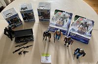 Overview of the lot showing four A-Team action figures, three Funko POP! figures in boxes, two packaged robot action figures, and miniature toy weapons with black case.