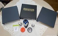 Full overview of the lot with three black card album binders and hockey memorabilia items arrayed on a table with a lace tablecloth