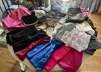 Clothing items and accessories spread on a white metal chair showing skirts, tops, sweaters, hats, and jewelry.