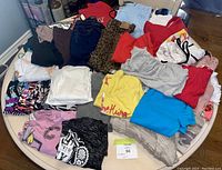 Photo showing a pile of assorted ladies extra small clothes of various colors and styles including tops and T-shirts, many look new or unworn.