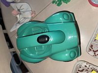 Teal plastic toy vehicle, closed, shaped like a small van or truck.