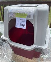 Front and slightly angled view of the covered cat litter box showing the red base and gray top with front flap.