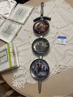 Full arrangement of sword vertically mounted with three circular Lord of the Rings collectible plates attached. Plates display detailed character and scene artwork. Styrofoam protective packaging opened and partially shown next to the items.