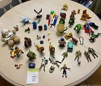 Overview photo of all toys laid out on a white round table including stuffed animal, action figures and various small toys