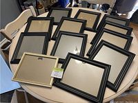 Overview of black picture frames, one gold-colored frame, displayed on a table