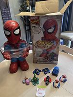 Vintage Spider-Man figure holding a clear bowl next to its original Marvel Comics box and a set of eight small plastic toys.
