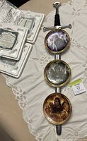 Overall view of the sword-shaped display mounted with the three Lord of the Rings character plates and certificates of authenticity in original packaging.