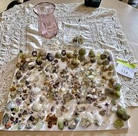 Wide top view of the assorted tumbled and raw crystals, garnet crystals, thundereggs, and geodes laid out on a white surface.