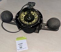 Front view of the vintage boat compass showing its compass rose, spherical floats on each side, mounting bracket, and adjustment knob.