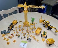 Full view of vintage yellow construction play set including tower crane, vehicles, signs, and accessories arranged on a table.