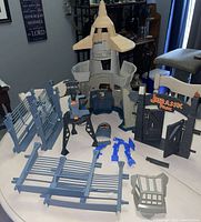 Wide shot of all playset pieces including lookout tower, fencing, gates, control box, and accessories on a table.