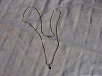 Full view of the gold chain necklace with pendant displayed on fabric backdrop