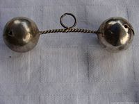 Front view of the antique sterling silver baby rattle showing twisted handle, loop and spherical bells with holes.