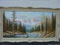 Full view of the framed landscape painting showing the river, trees, and mountains.