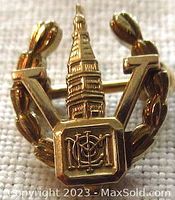Front view of the 14K gold Birks victory pin showing tower, laurel elements, and monogram detail.