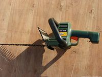 Side view of the Black & Decker electric hedge trimmer showing handle, hand guard, and blade.