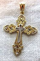 Close-up photo of 10K yellow gold cross pendant showing front view with open scroll filigree design and central raised cross element.