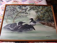 Full view of the framed oil painting featuring two loons in a natural water setting with trees in the background.