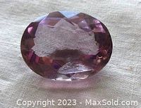 Top view of oval amethyst gemstone showing the faceted surface and color.
