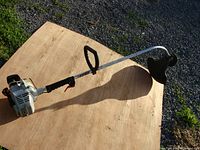 Full weed eater gas-powered ECHO GT-200R with curved metal shaft, protective guard, and handle grip on wooden surface outdoors.