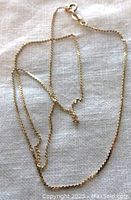 Full length of delicate 16-inch vintage gold chain necklace laid out on fabric.