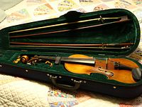 Photo showing vintage 4/4 violin in hard case with green velvet lining and two bows inside
