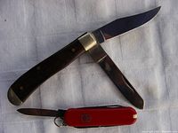 Photo showing the vintage Browning folding knife with two blades open next to the small red Victorinox mini multi-tool.