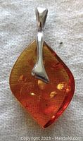 Close-up of amber pendant front showing translucent amber with natural inclusions and silver bail.
