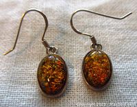 Front view of amber cabochon set in sterling silver drop earrings showing color and clarity of amber stones