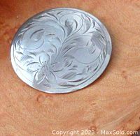 Close-up of front side showing detailed floral engraving on silver brooch
