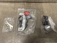 Bike reflectors and tool kit in plastic bags on concrete floor.