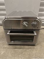 Front view of Cuisinart air fryer toaster oven showing temperature and time dials, front glass door and handle.
