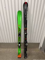 Pair of skis side by side showing one green Elan Sick Rip and one black Rossignol ski with bindings