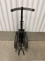 Full view of the black folding golf push cart showing handle, wheels, and frame.