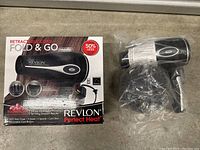 Photo showing the Revlon Perfect Heat Fold & Go hair dryer alongside its original box, featuring product details and branding.
