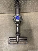 Top view of Dyson handheld vacuum cleaner showing roller brush head attachment and cyclone cone motor housing.