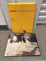 Photo of Kodak Professional packaging used for photographic prints and a printed photo featuring John Lennon and Yoko Ono sitting together with Lennon holding a guitar.