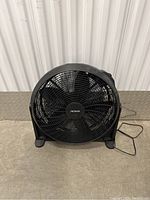Front view of the black Noma fan showing its protective grille, brand logo in center, and three fan blades.
